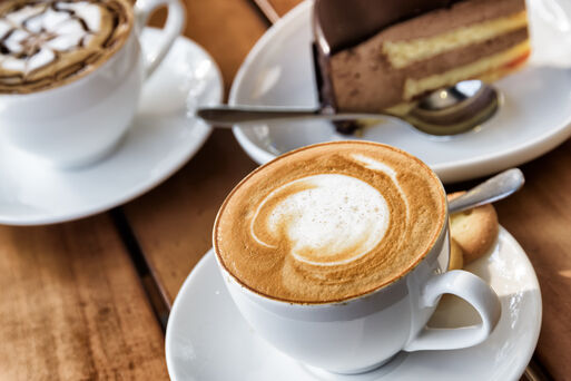 Cup of hot Cappuccino coffee on wooden table at cafe