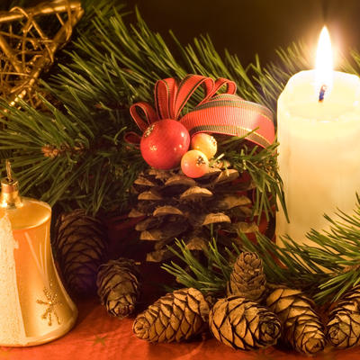 Weihnachtsgesteck mit brennender Kerze und Tannengrün
