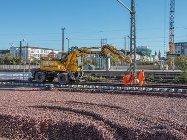 Bild vergrößern: Arbeiter verlegen Gleise auf dem neu angelegten Schotterbett. 11/16