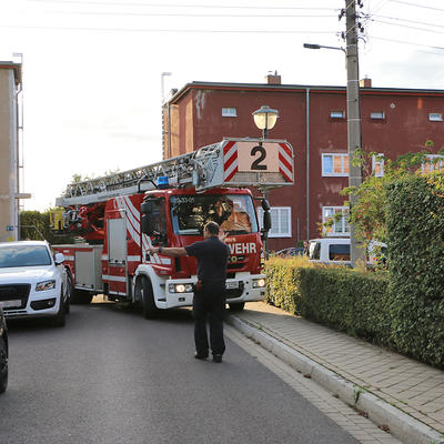 Drehleiterwagen der Feuerwehr fährt eine enge Kurve im Wohngebiet