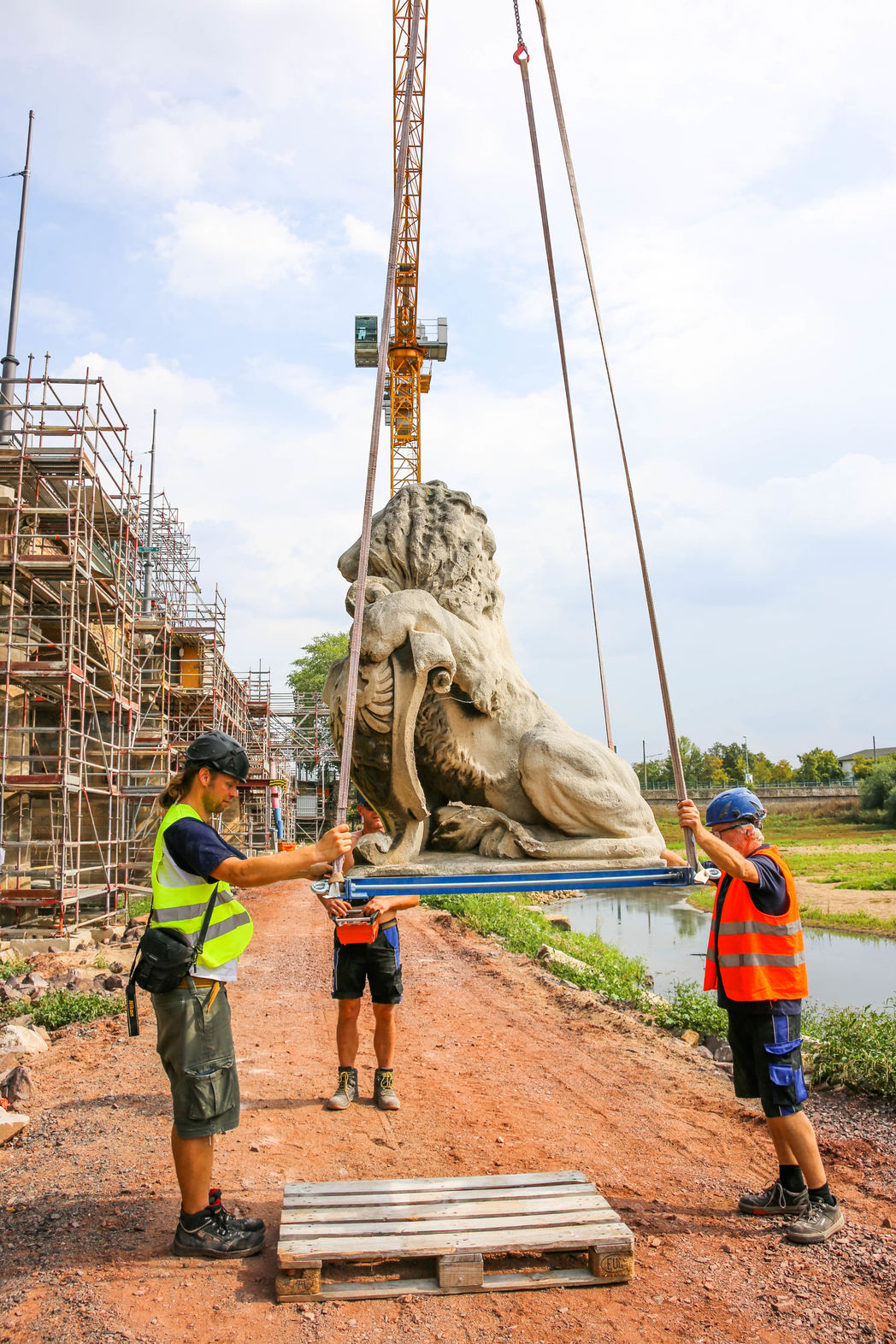Der Löwe wird auf die Baustelle neben die Brücke transportiert.
