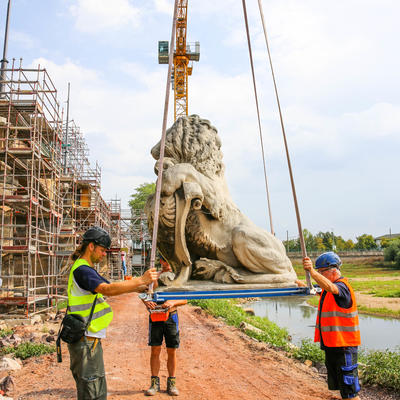 Der Löwe wird auf die Baustelle neben die Brücke transportiert.