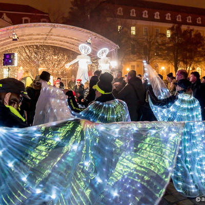 Beleuchtete Mäntel und Lichtengel auf der Bühne des Weihnachtsmarktes