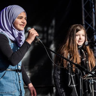 Mädchen auf der Bühne des Schul-Campus mit einem Mikrofon in der Hand