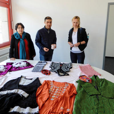Gäste des Integrationsprojekt-Büros schauen sich landestypische Kleidung an