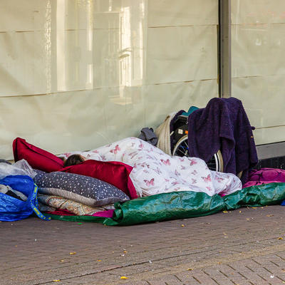 Obdachlosenlager mit Decken, Kissen und einem Rollstuhl
