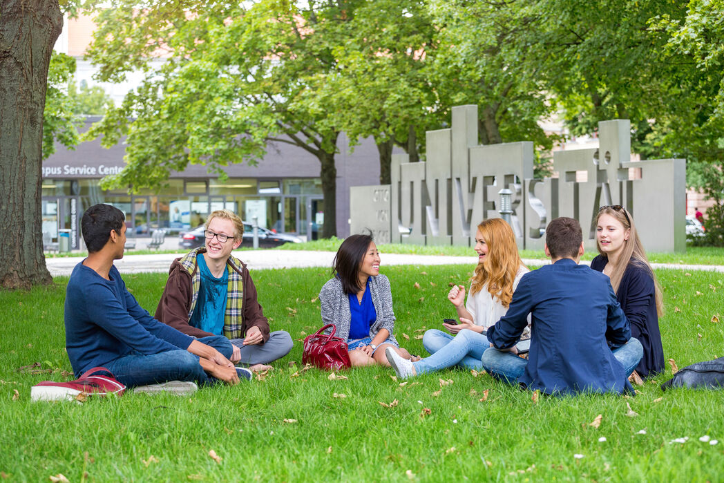 Bild vergrößern: Studierende auf dem Campus der Otto-von-Guericke-Universität Magdeburg vor der Uniporta.