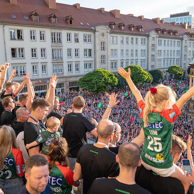Spieler des SC Magdeburg mit hochgerissenen Armen auf dem Rathausbalkon