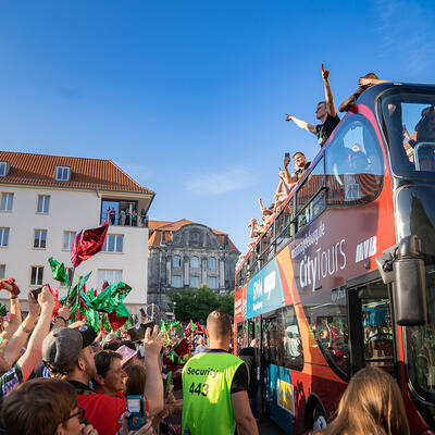 Spieler des SC Magdeburg jubeln ihren Fans vom Bus vor dem Rathaus aus zu