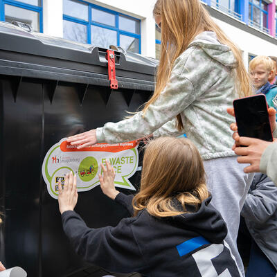 Kinder des Magdeburger Stiftungsgymnasiums bekleben eine Tonne mit E-Waste Race