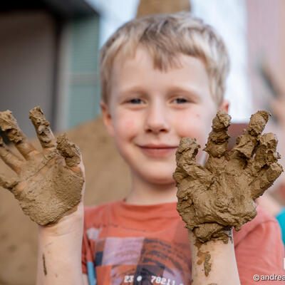 Kind zeigt sandbeklebte Hände in die Kamera