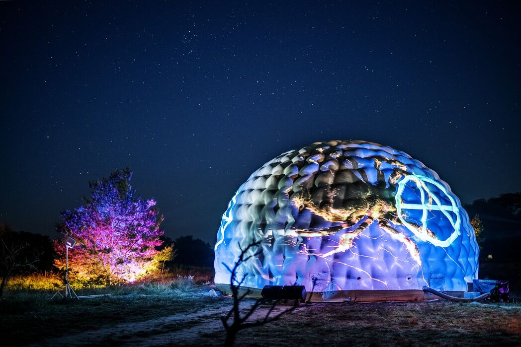 Farblich beleuchtetes Kugelgebude bei Nacht
