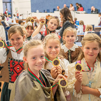 Kinder zeigen freudig Zertifikate in Form einer Medaille »Magdeburger Recht«