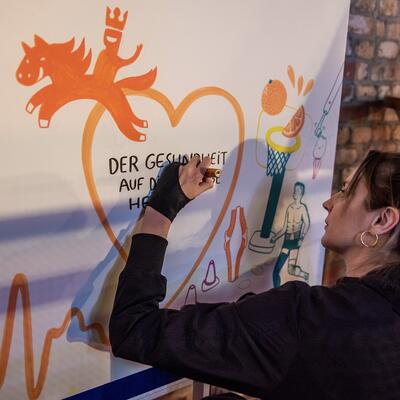 Ausstellerin zeichnet an einem Whiteboard zur Gesundheitsmesse Magdeburg