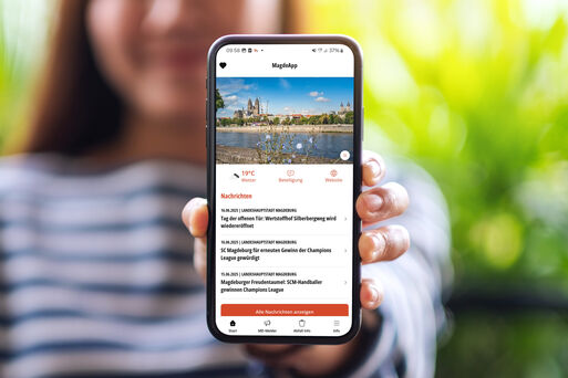 Frau mit einem Handy und der Magdeburger "MagdeApp"